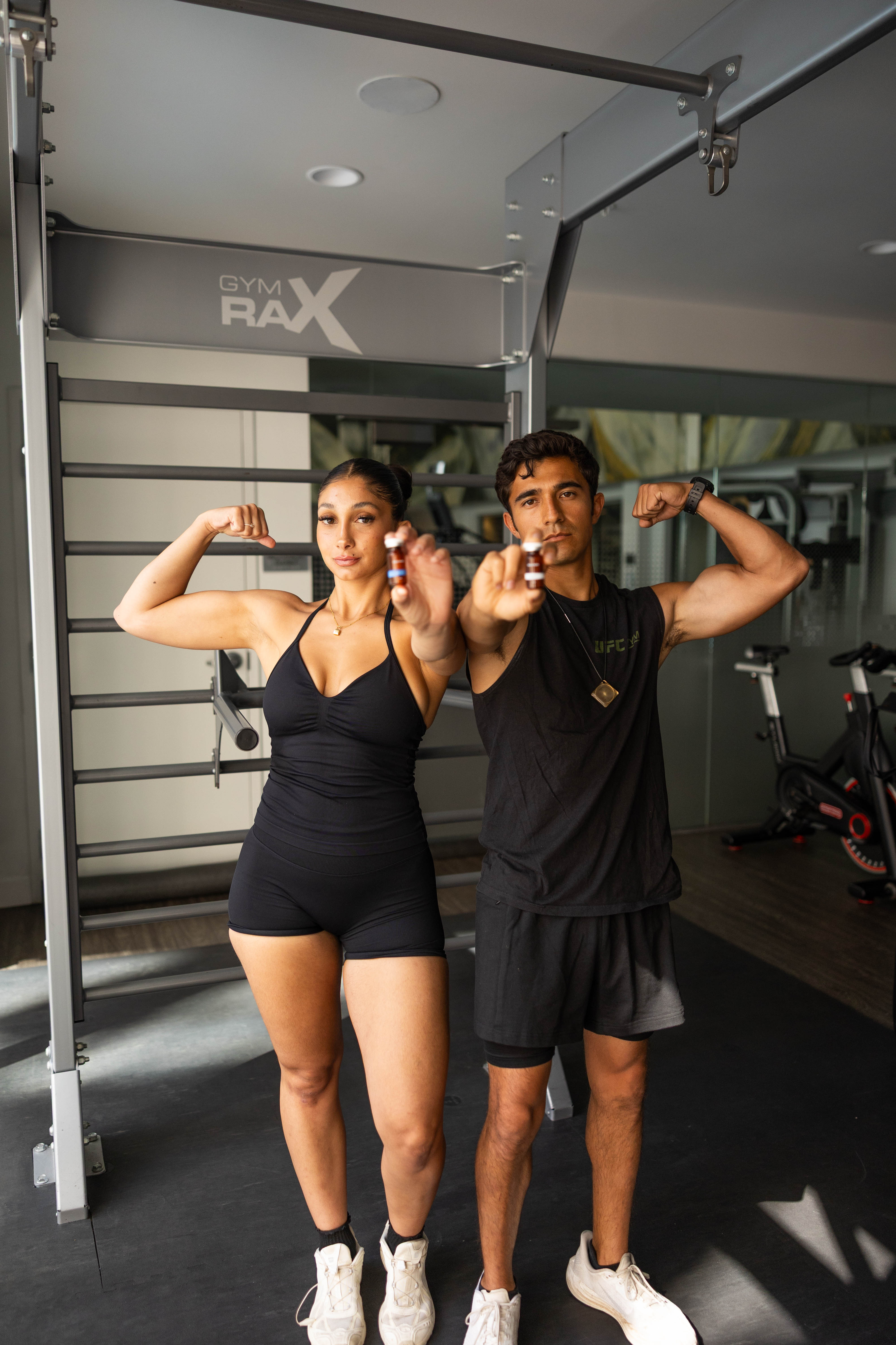 Two athletes flexing and holding up their Buena Health peptide vials