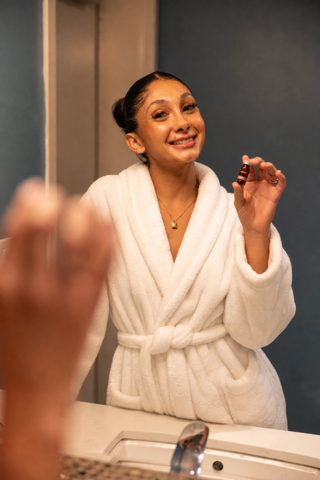 A patient holding up a SkinRx prescription serum vial during her at-home routine